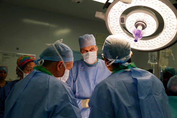 SUTTON, UNITED KINGDOM - NOVEMBER 07: Prince William, Duke of Cambridge, in his role as President of the Royal Marsden NHS (National Health Service) Foundation Trust, listens to head surgeon Pardeep Kumar (R) as he observes surgery for the removal of a bladder tumour on a male patient during a visit to the Royal Marsden Hospital on November 07, 2013 in Sutton, Greater London. (Photo by Lefteris Pitarakis - WPA Pool/Getty Images)