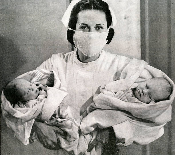 A nurse holds newborn twins in a hospital maternity ward, 1944. Screen print. (Photo by GraphicaArtis/Getty Images)