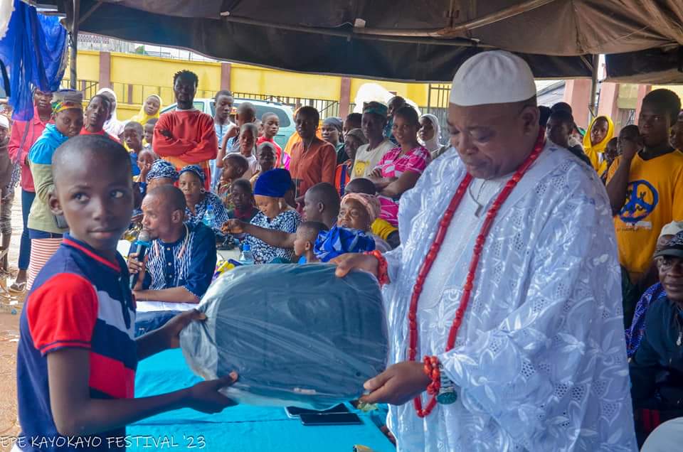 High Chief Adeniyi Kadri Odedeogboro, the Balogun of Epe kingdom presents a gift to one of the winners