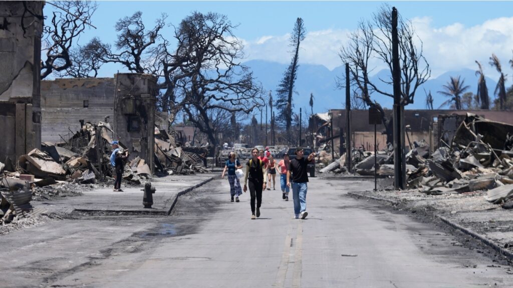 People walk along Main Street past wildfire damage on August 11, 2023, in Lahaina, Hawaii (Photo: Rick Bowmer)