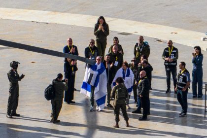 A released hostage, Ohad Ben Ami, draped in an Israeli flag gives a thumbs up after he arrives at Tel Aviv Sourasky Medical Center-Ichilov Hospital on Saturday.Alexi J. Rosenfeld / Getty Images