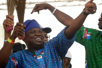 Former Lagos State Governor, Akinwunmi Ambode, in an APC-themed attire while holding a broom, the party's symbol